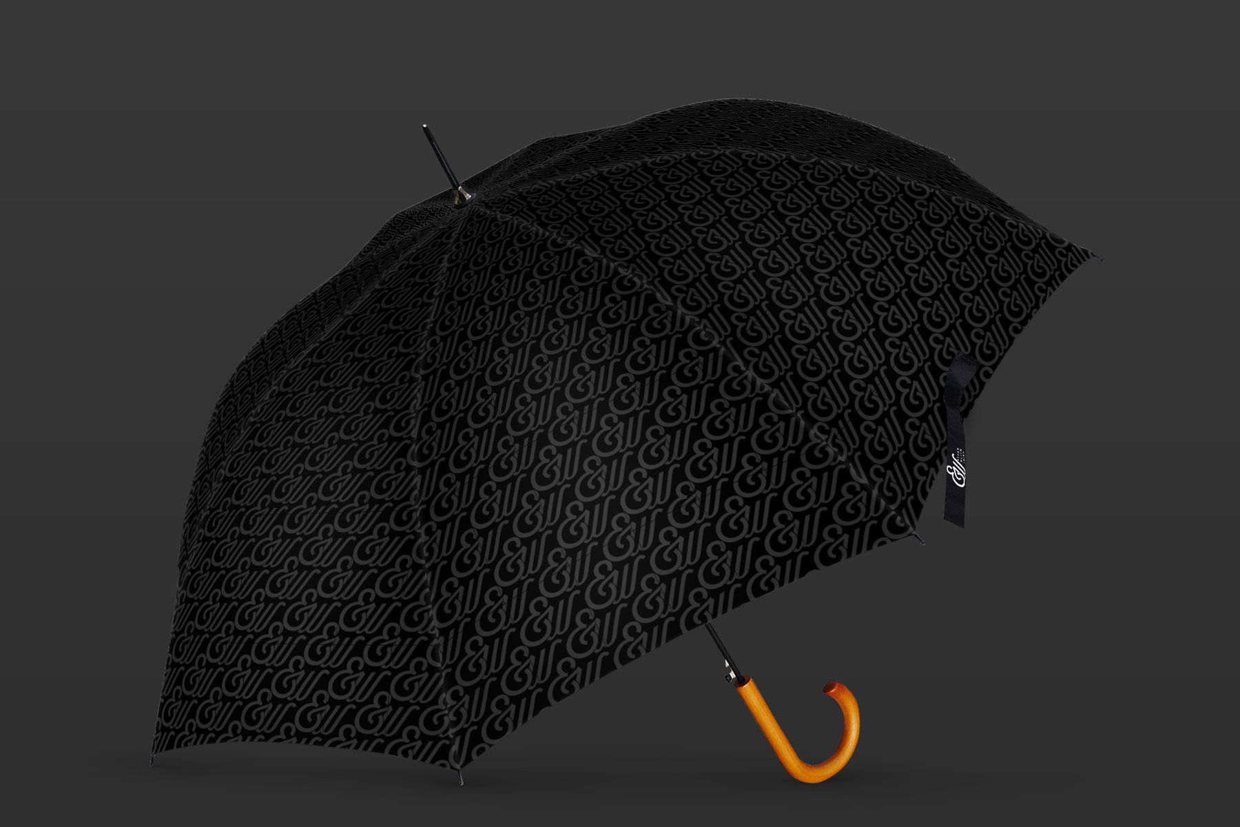 A black umbrella with a wooden handle, its canopy covered in the tone-on-tone monogram pattern